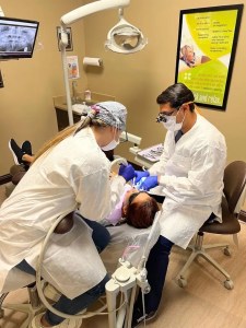 Dentists treating a child patient in clinic chair