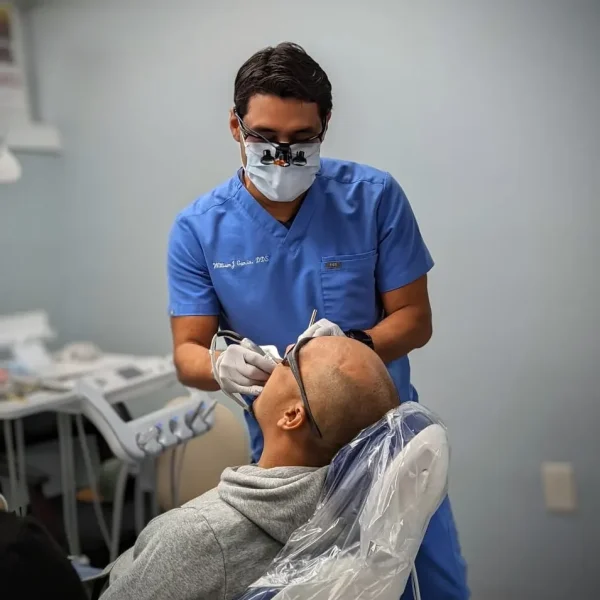 Dr. García trabajando con un paciente en el sillón de examen.