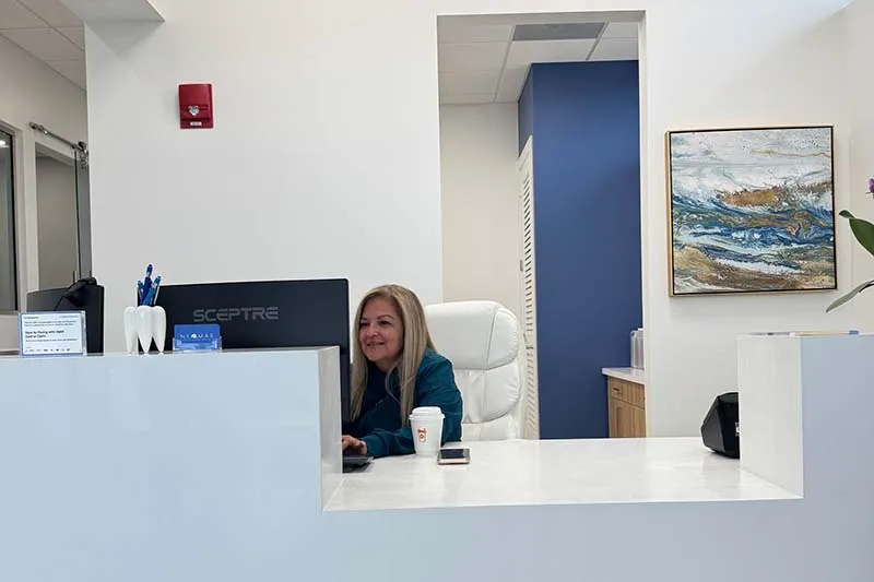 Recepcionista de recepción en su escritorio, sonriente